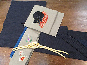 縞結城袷着物と座布団の上の黒猫刺繍名古屋帯